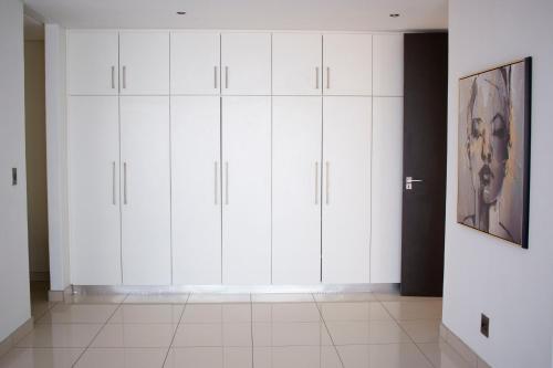 a white closet with white cabinets in a room at Guest House Auasblick by State House in Windhoek