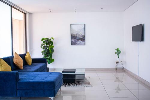 a living room with a blue couch and a tv at Guest House Auasblick by State House in Windhoek