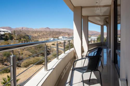 a balcony with a chair and a view of the desert at Guest House Auasblick by State House in Windhoek