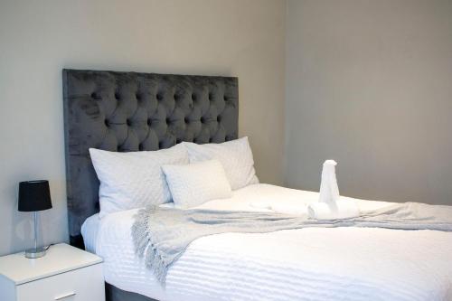 a bedroom with a white bed with a gray headboard at Guest House Auasblick by State House in Windhoek