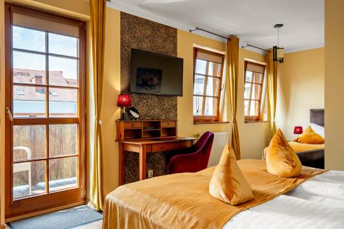 a hotel room with a bed and a desk and a window at Pensjonat Miejski in Zgorzelec