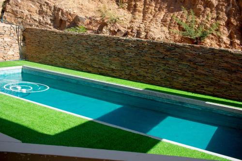a swimming pool with grass and a brick wall at Guest House Auasblick by State House in Windhoek