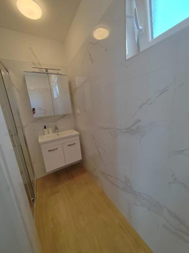 a white bathroom with a sink and a mirror at Martina in Rab