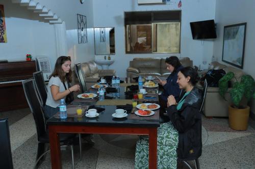 three women sitting around a table eating food at Mowicribs Hotel and Spa in Entebbe