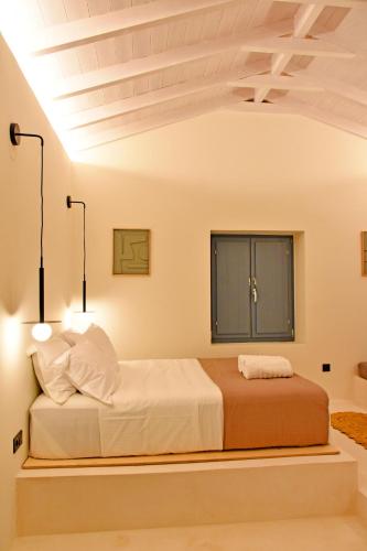 a bedroom with a bed with two lights on it at Opuntia Boutique Hotel in Kalívia