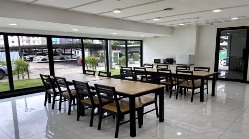 a dining room with tables and chairs and windows at OK Hotel Bangkok in Bangkok