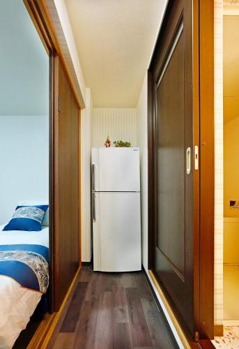 a small room with a refrigerator and a bed at 鹿の宿 in Osaka