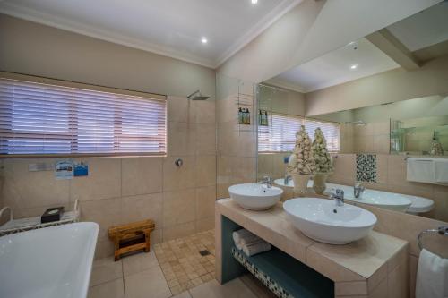 a bathroom with two sinks and a tub at On the Beach Guesthouse Jeffreys Bay in Jeffreys Bay