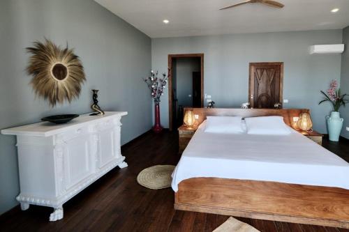 a bedroom with a large white bed and wooden floors at Maharaja Boutique Hotel Zanzibar in Uroa