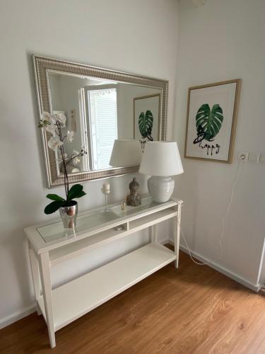 a white console table with a mirror and a lamp at Calma bungalows in Portorož