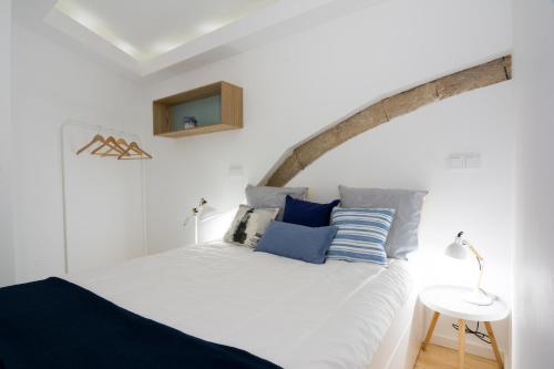a bedroom with a white bed with blue pillows at Casa do Castelo 1- Work or Relax in the Historic heart of Lisbon! in Lisbon