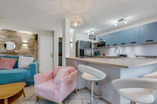 une cuisine et un salon avec une chaise rose dans l'établissement Mer et Toison d'or - Duplex entièrement climatisé, au Cap d'Agde