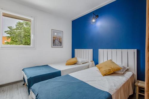 - 2 lits dans une chambre avec un mur bleu dans l'établissement Mer et Toison d'or - Duplex entièrement climatisé, au Cap d'Agde