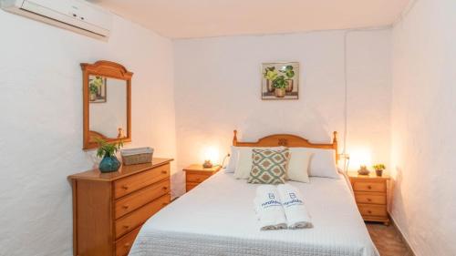 a bedroom with a white bed and a wooden dresser at Casa Pulirio Antequera - La Higuera by Ruralidays in Antequera