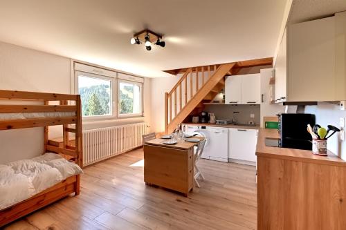 Il comprend une chambre avec des lits superposés et une cuisine avec un bureau. dans l'établissement Le Nid des Vosges - Appt vue montagne, à Gérardmer
