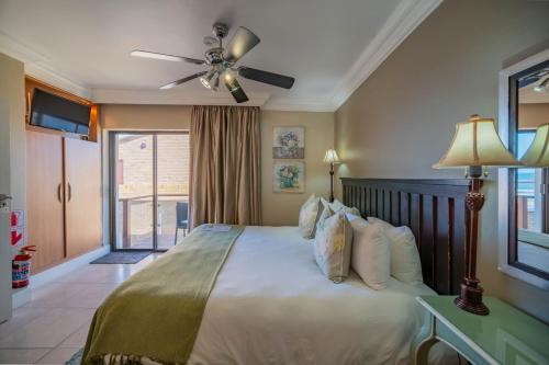 a bedroom with a large bed with a ceiling fan at On the Beach Guesthouse Jeffreys Bay in Jeffreys Bay