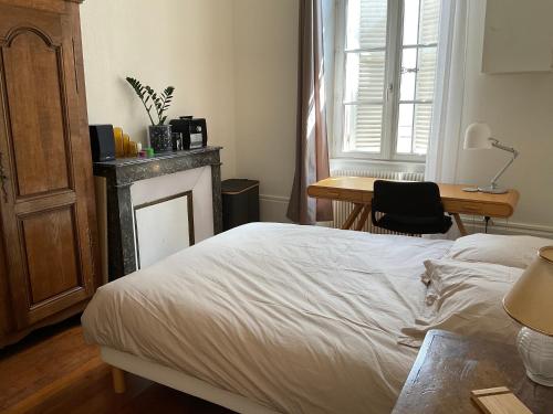 a bedroom with a bed and a desk and a table at Petit appartement douillet, centre historique de Dijon in Dijon