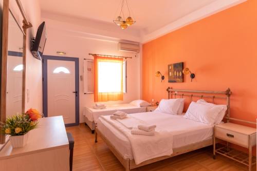 two beds in a room with orange walls at Coralli Rooms & Restaurant in Elafonisos