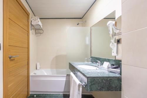 a bathroom with a sink and a tub and a mirror at Moon Dreams Calabahía in Cala del Moral