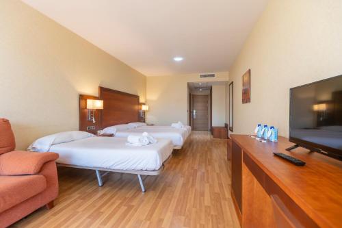 a hotel room with three beds and a flat screen tv at Moon Dreams Calabahía in Cala del Moral