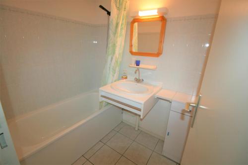 une salle de bain blanche avec un lavabo et une baignoire dans l'établissement La Grière domaine Sainte Anne avec piscine, à La Tranche-sur-Mer