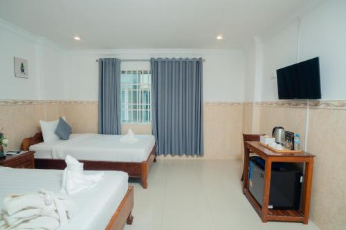 a hotel room with two beds and a television at White Corner Hotel in Phnom Penh