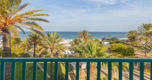 a balcony with a view of the beach and palm trees at El Mouradi Port El Kantaoui in Port El Kantaoui