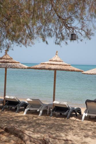 a row of chairs and umbrellas on the beach at Coralli Rooms & Restaurant in Elafonisos