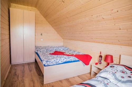 a small bedroom with a bed in a wooden cabin at Baltic Holiday in Dębki