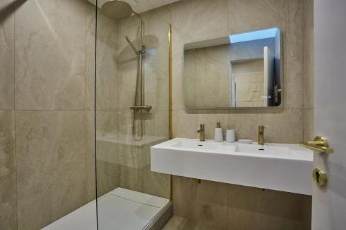 une salle de bain avec un lavabo blanc et un miroir dans l'établissement Place de la Bastille Cozy and Modern 2BD, à Paris
