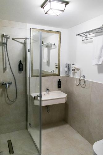 a bathroom with a sink and a shower with a mirror at Hotel Gradina Morii in Sighetu Marmaţiei