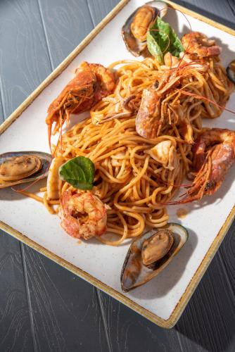 a plate of spaghetti and shrimp on a table at Coralli Rooms & Restaurant in Elafonisos