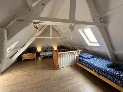 Cette chambre mansardée comprend 2 lits et une fenêtre. dans l'établissement Entre pierres & mer, à Fresville