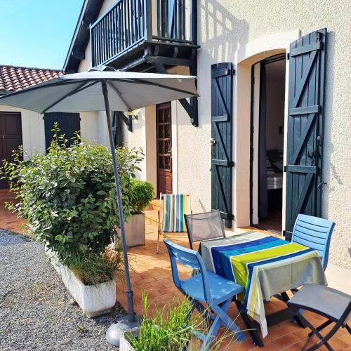 a patio with a table and an umbrella at Cocooning et plages in Capbreton