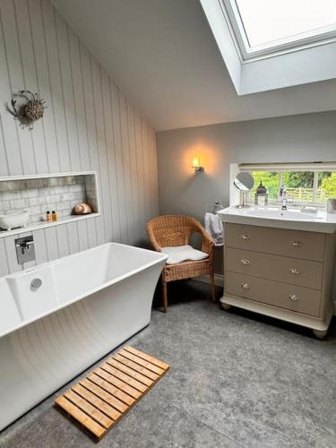 a bathroom with a tub and a sink and a chair at Luxury Barn with sauna near York welcoming families, friends, groups in York