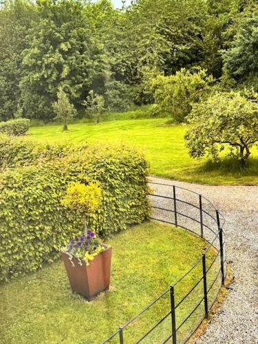 a fence with a pot of flowers in the grass at Luxury Barn with sauna near York welcoming families, friends, groups in York