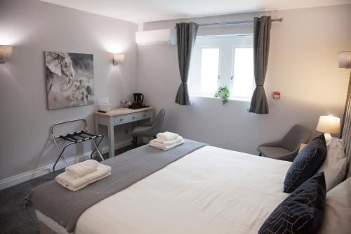 a bedroom with a large white bed and a desk at Shendish Manor Hotel & Golf Course in Hemel Hempstead
