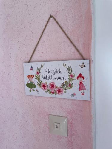 a sign hanging on a pink wall with flowers at Plasur - Apartement Bella Vista in Montechiaro