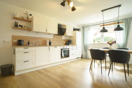 a kitchen with white cabinets and a table and chairs at Ferienwohnung Hyggelig in Waldershof