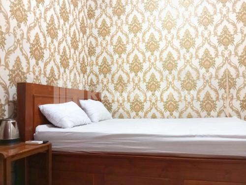 a bed with white pillows in a bedroom with a wallpaper at Isa Homestay Kudus Mitra Reddoorz in Kudus