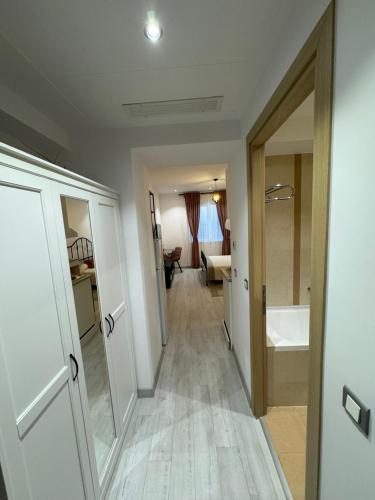 a hallway leading to a bathroom with a tub and a sink at La Mika -Your Home in Bucharest