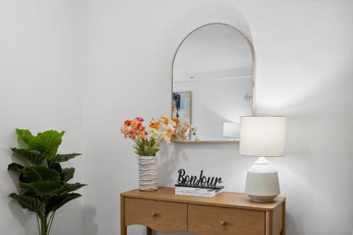 a table with a mirror and a vase with flowers at Cozy City Apartment with Stunning Views and Ameni in Perth