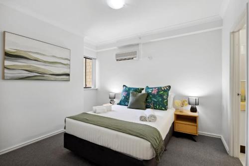 a white bedroom with a bed and a night stand at Cozy City Apartment with Stunning Views and Ameni in Perth