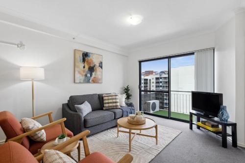 a living room with a couch and a tv at Cozy City Apartment with Stunning Views and Ameni in Perth