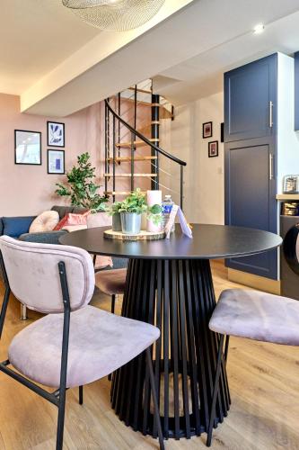 une salle à manger avec une table et des chaises noires dans l'établissement Le Madeleine chez les M by Primo C0nciergerie, à Nevers