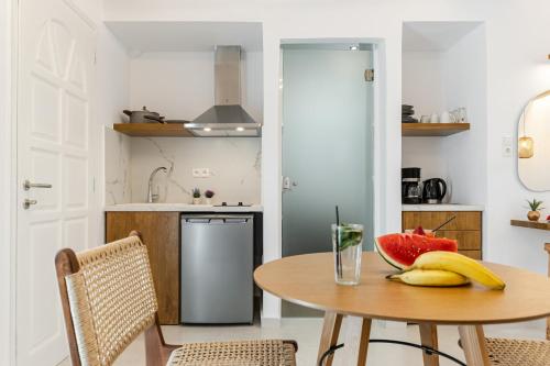 a kitchen with a table with a bowl of fruit on it at Birikos Hotel & Suites in Agios Prokopios