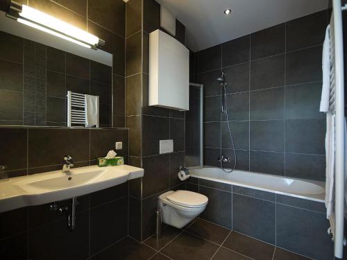 łazienka z toaletą, umywalką i wanną w obiekcie Apartments Obernosterer w Kaprunie