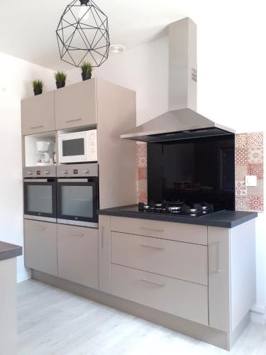 une cuisine avec des appareils blancs et un comptoir noir dans l'établissement Gîte de l'Orangerie, 15 personnes, 7 ch, 275 m², à Saint-Gervais-la-Forêt