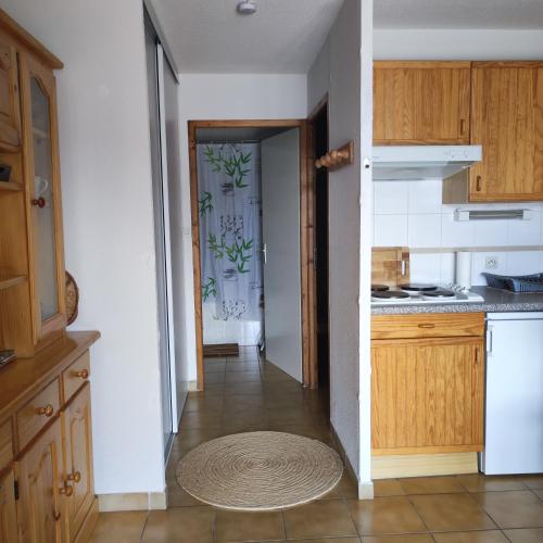 une cuisine avec des placards en bois et un couloir avec une porte dans l'établissement Appartement les Angles, aux Angles