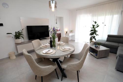 a living room with a dining table and chairs at New luxury air-conditioned apartment, with jacuzzi, free parking and gardens in Pula